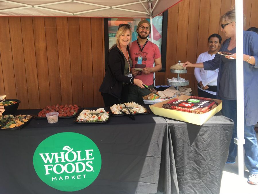 Whole Foods employees serve free food to passing students and administrators during the new food pantrys grand opening ceremony. 